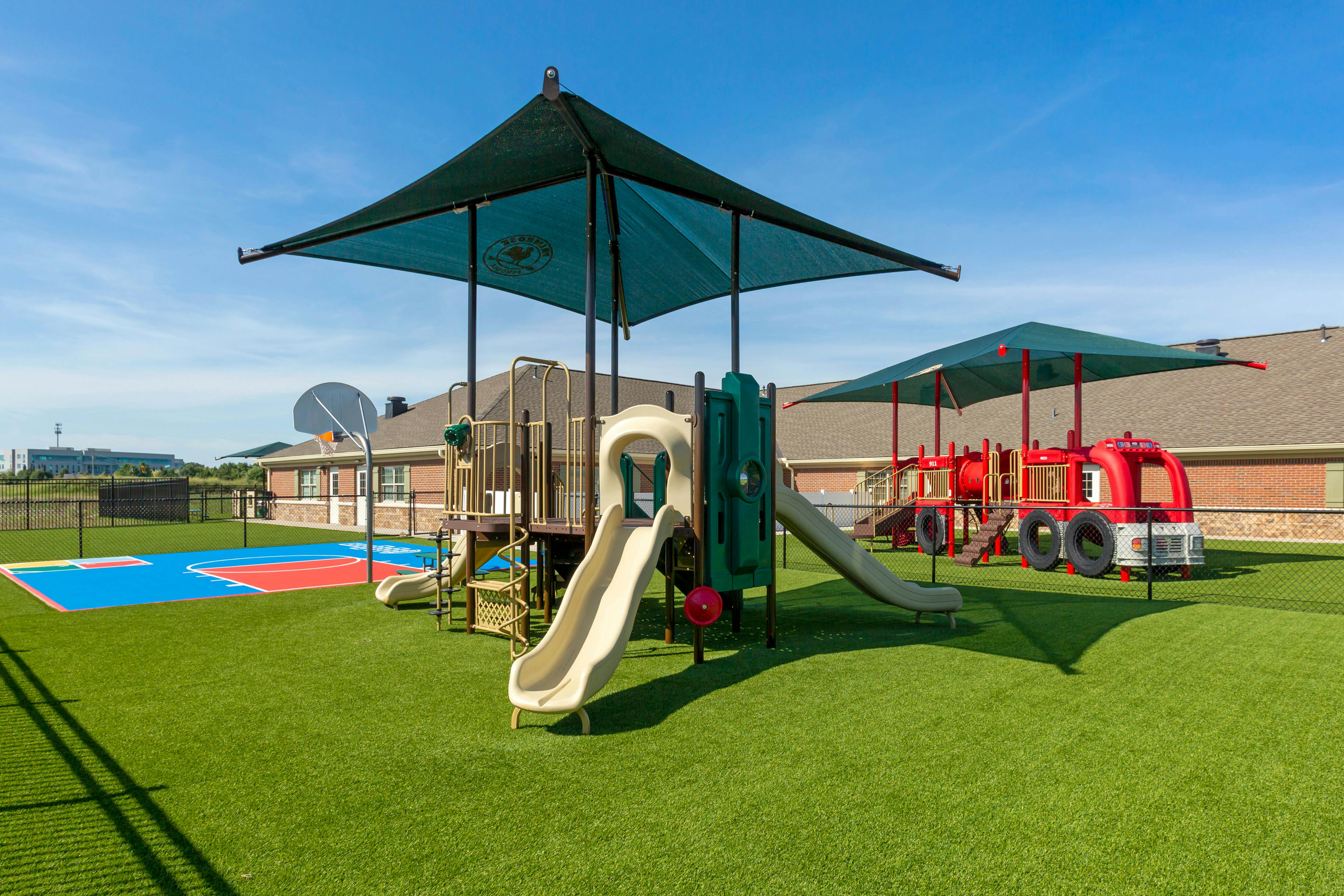 Outdoor playground with slides, climbing structures, and a fire truck play area