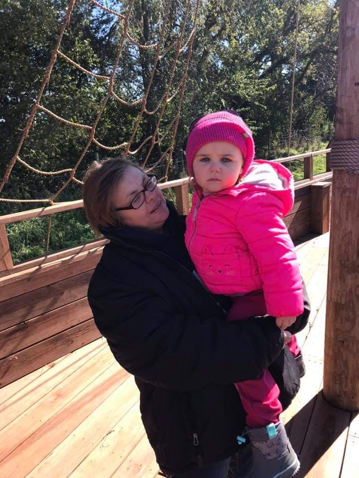 Person holding a child in a pink jacket and hat