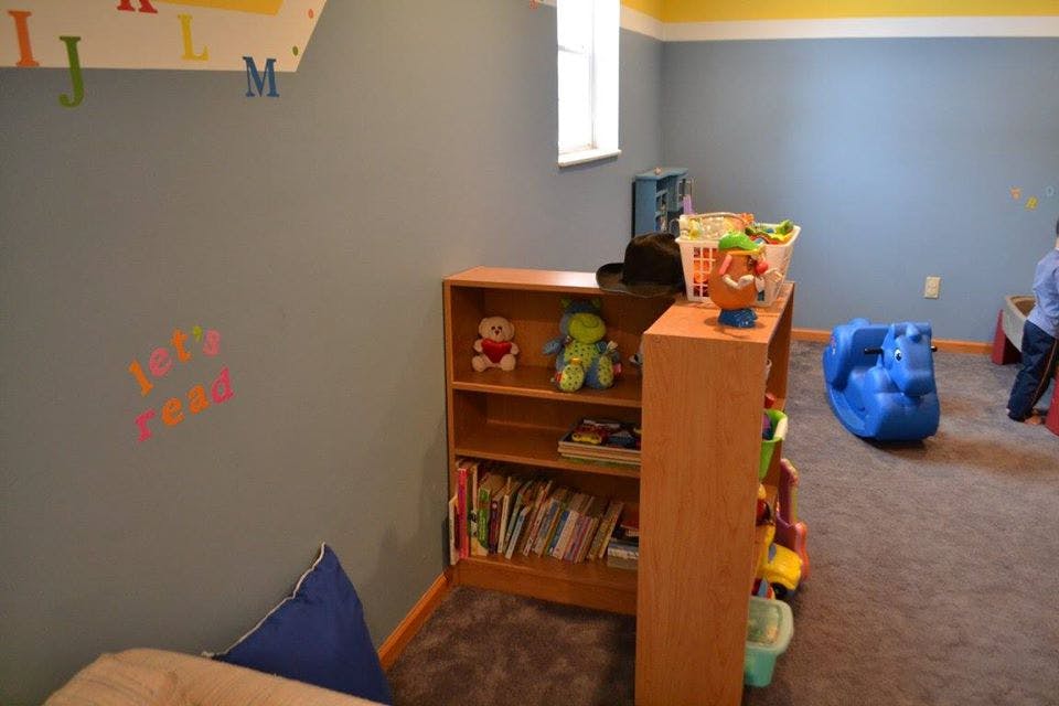 Playroom with bookshelves, toys, and a blue rocking toy