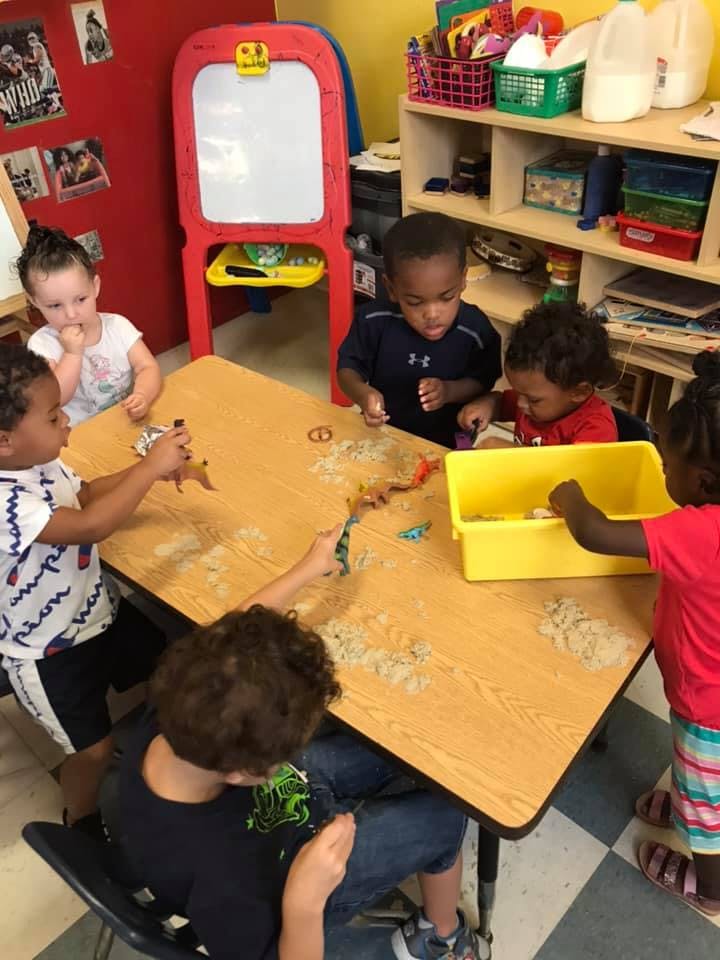 Children playing with toys at a table in a classroom