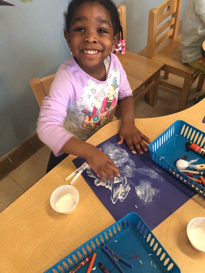 Child doing an art project with glue on blue paper