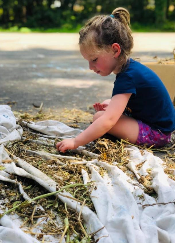 Child sitting on ground, reaching for debris