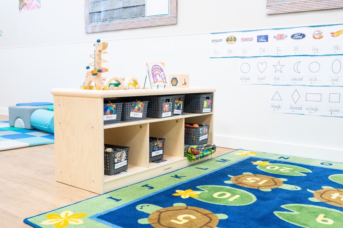 Wooden storage shelf with labeled toy bins in a preschool classroom