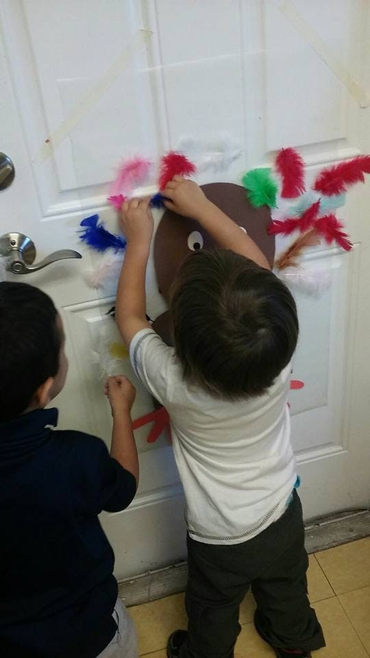 Two children decorating a door with a turkey craft