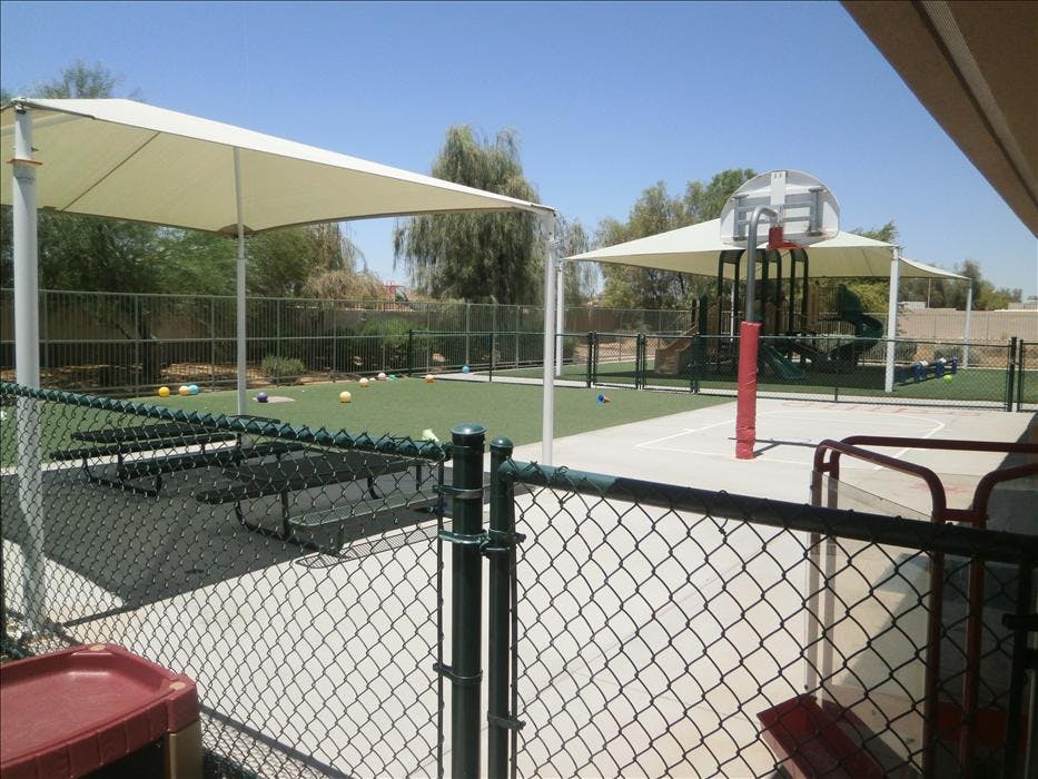 Outdoor playground with artificial turf, picnic tables, and a basketball court