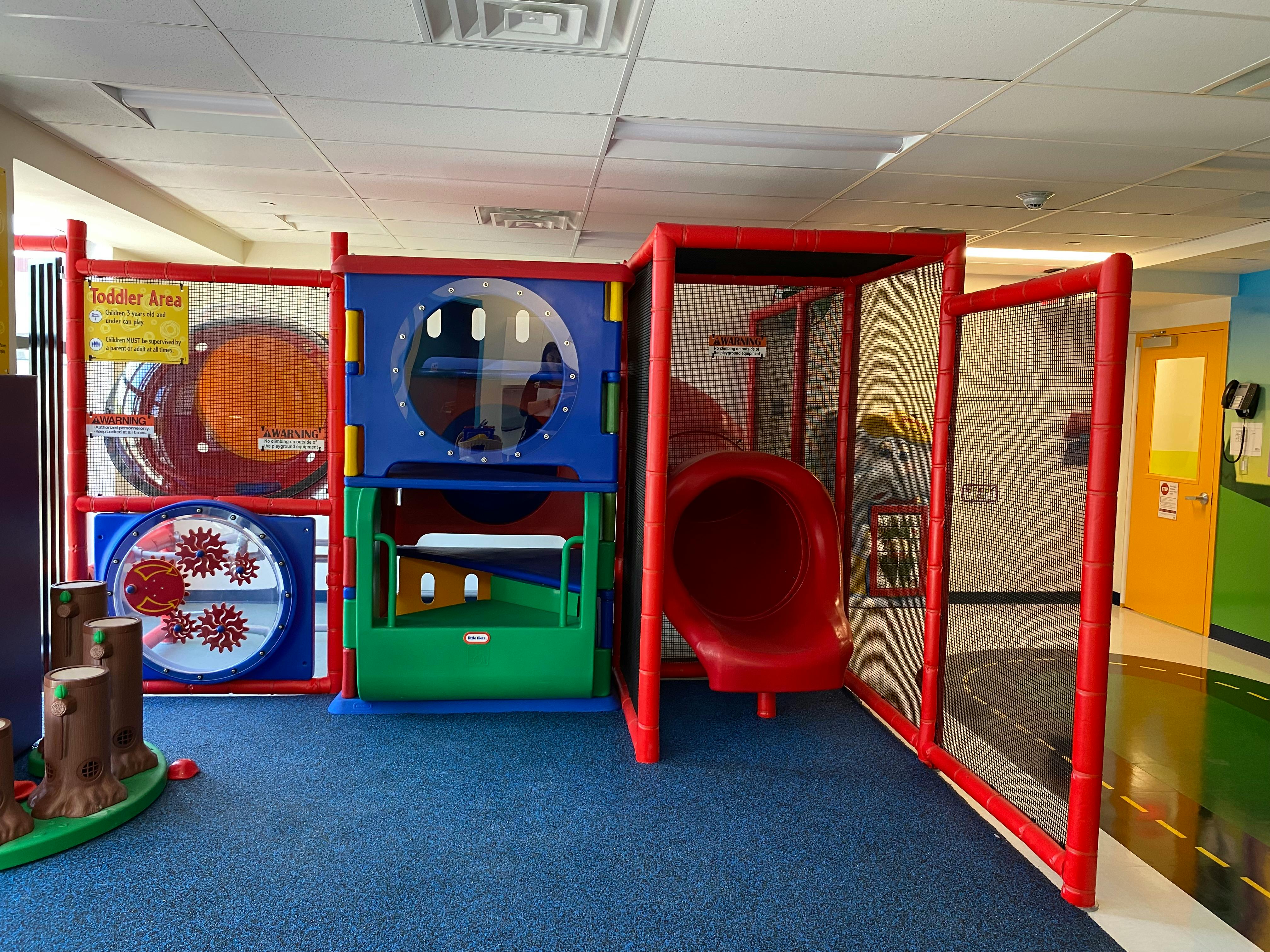Indoor playground with red slide and activity panels