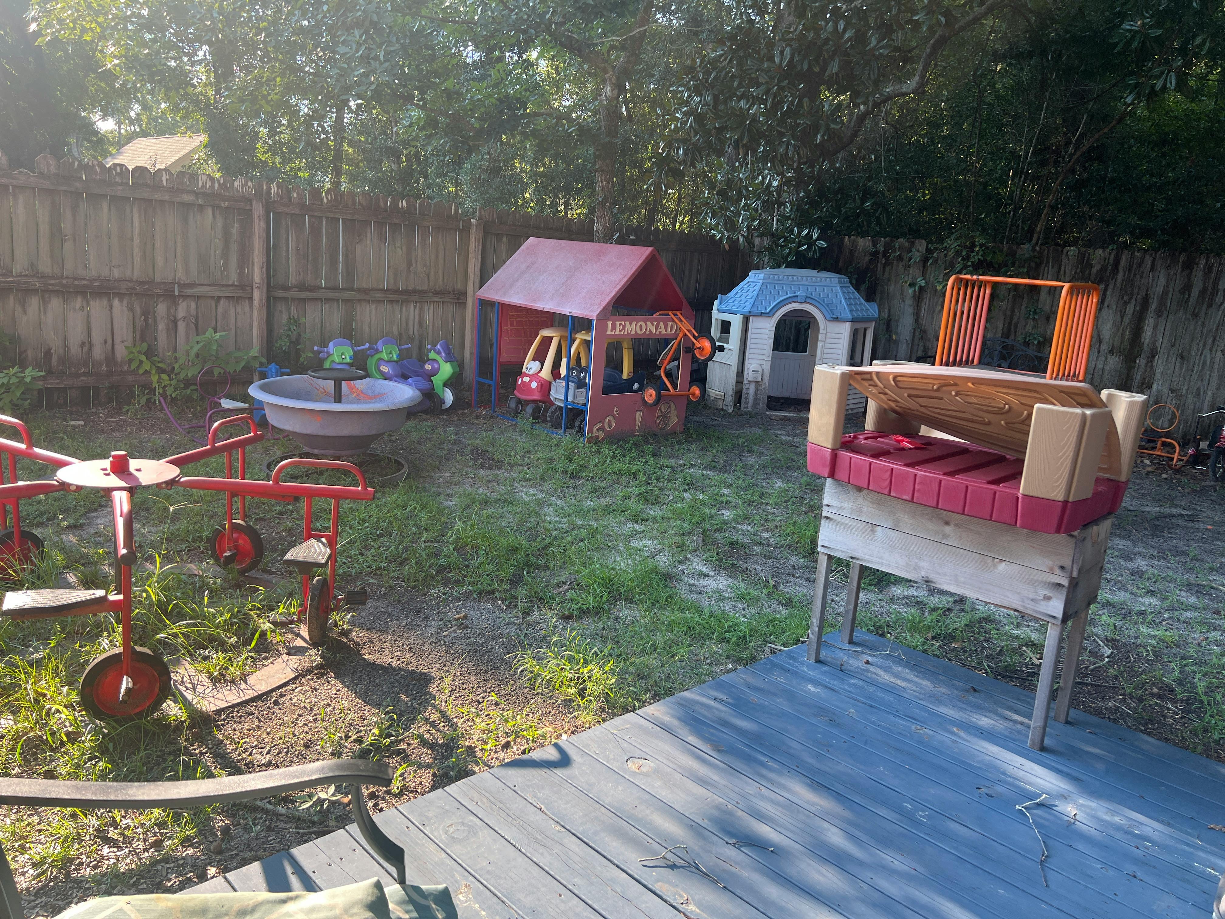 Backyard with playhouses, sandbox, and children's ride-on toys