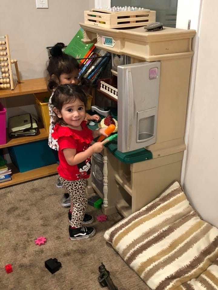 Two children playing with a toy kitchen set