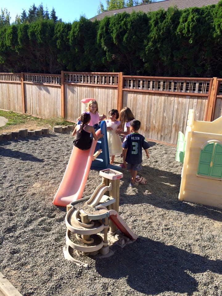 Children playing on a slide and playground equipment in a sandy area
