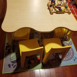Children's table with two yellow chairs and a toy on top