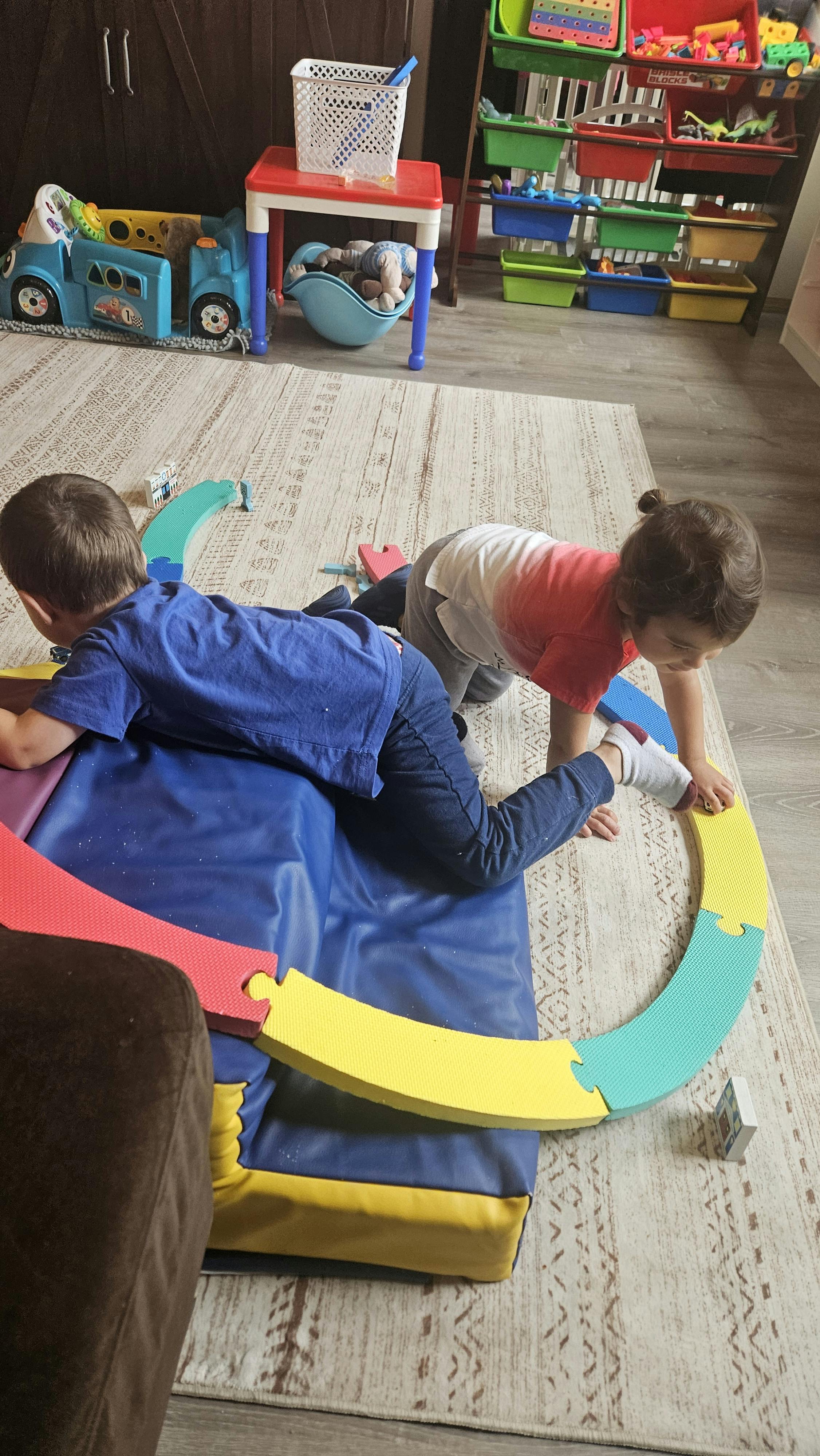 Two children playing with colorful foam pieces on a mat