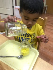 Child pouring liquid from one jar into another