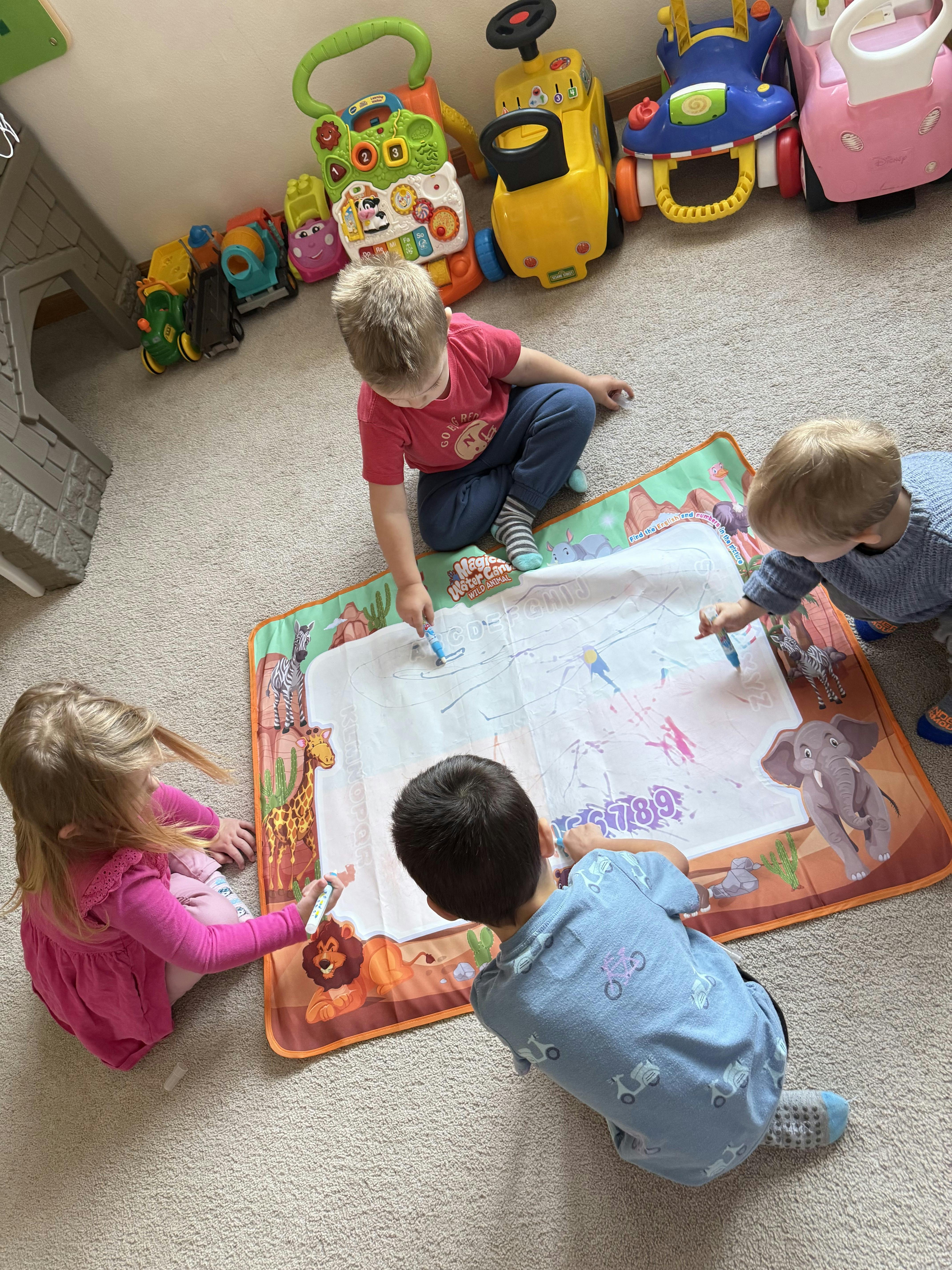 Children drawing on a mat with pens