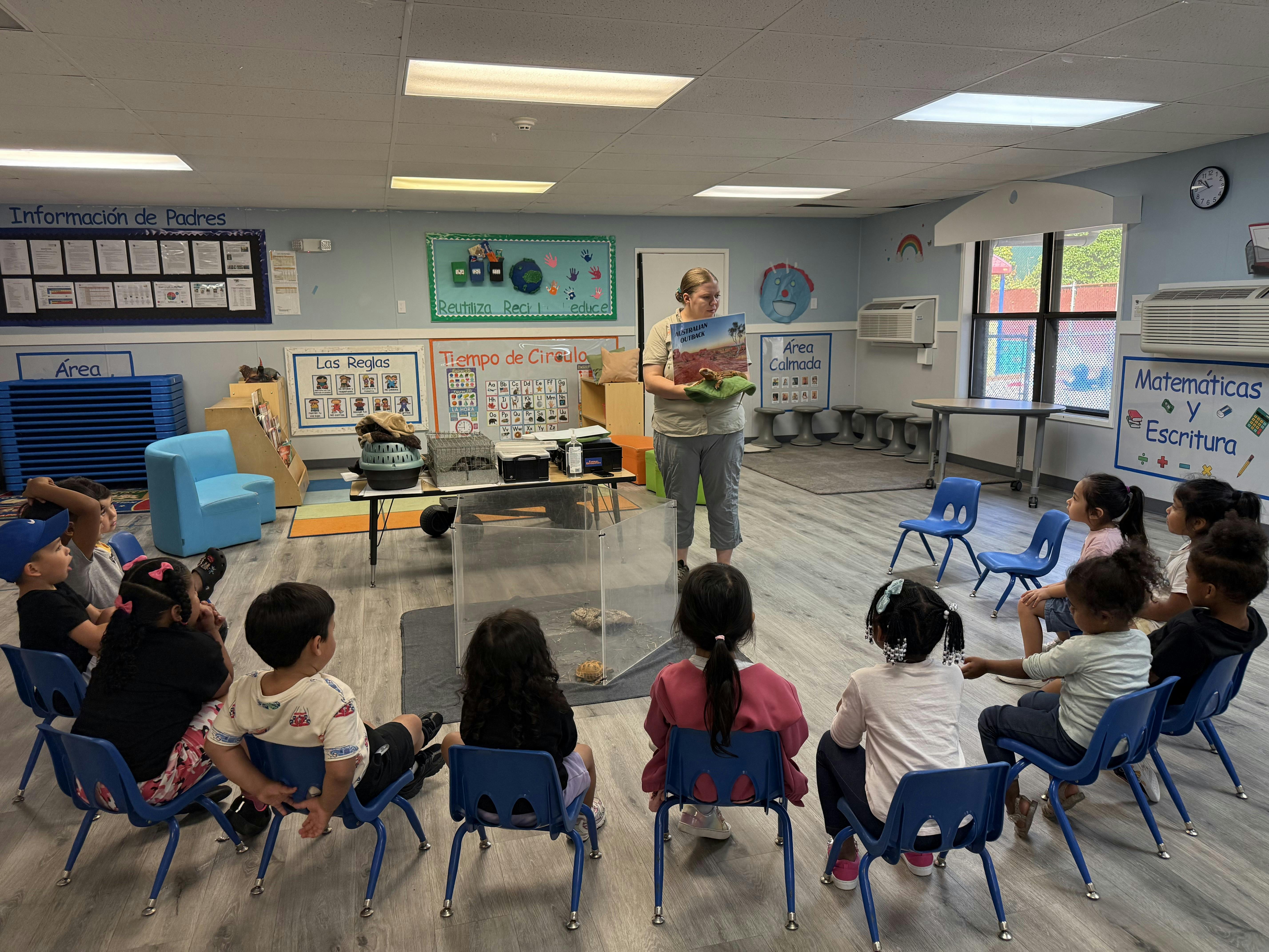 Person reading a book to a group of children sitting in a circle