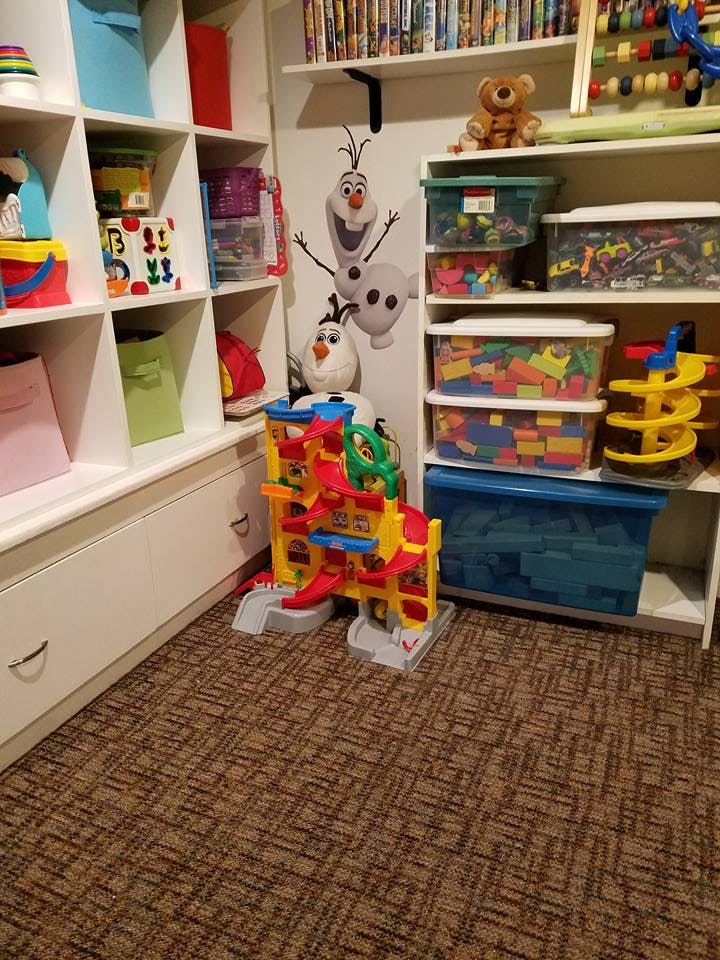 Playroom with shelves of toys and a colorful toy car ramp