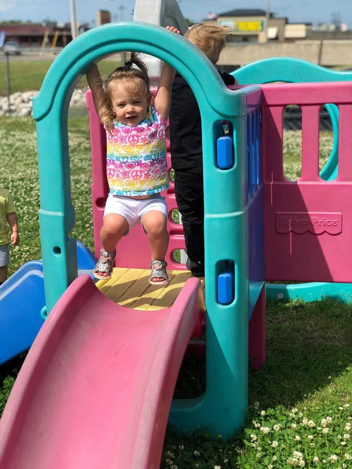 Child holding onto a play structure bar above a slide