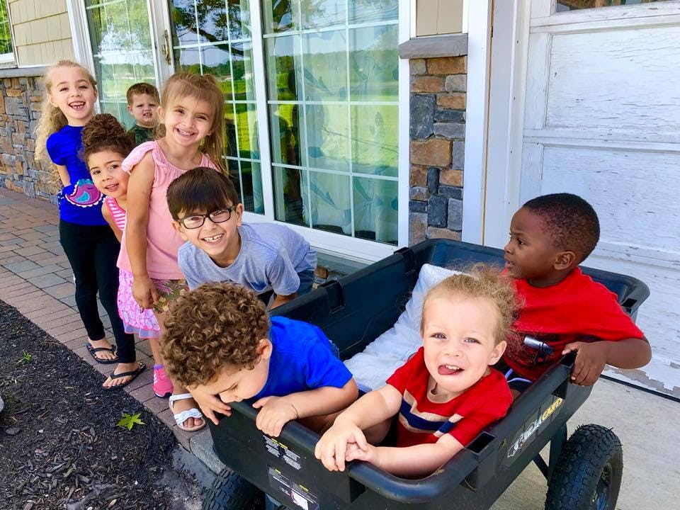 Group of children and teens playing with a wagon outdoors
