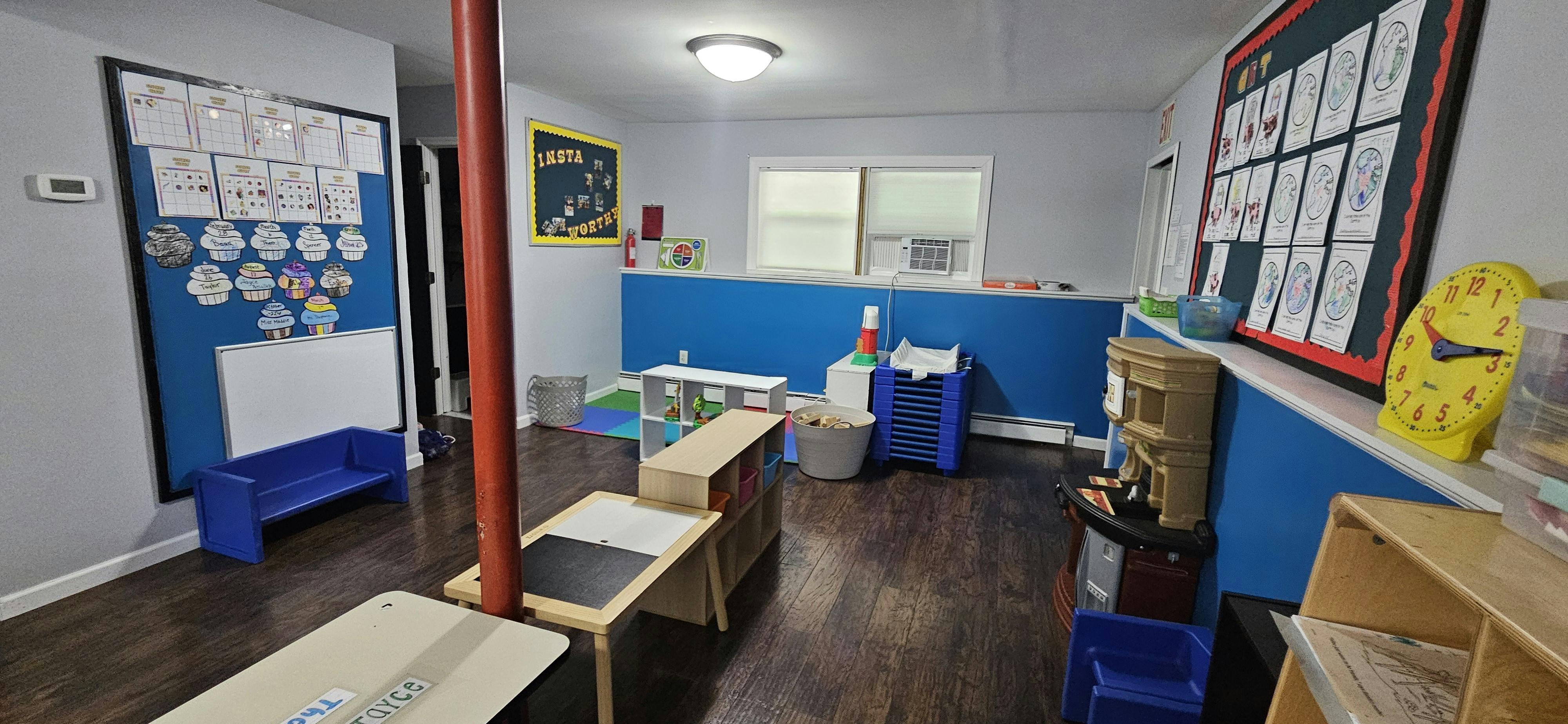 Classroom with blue walls, calendar, learning materials, and play kitchen