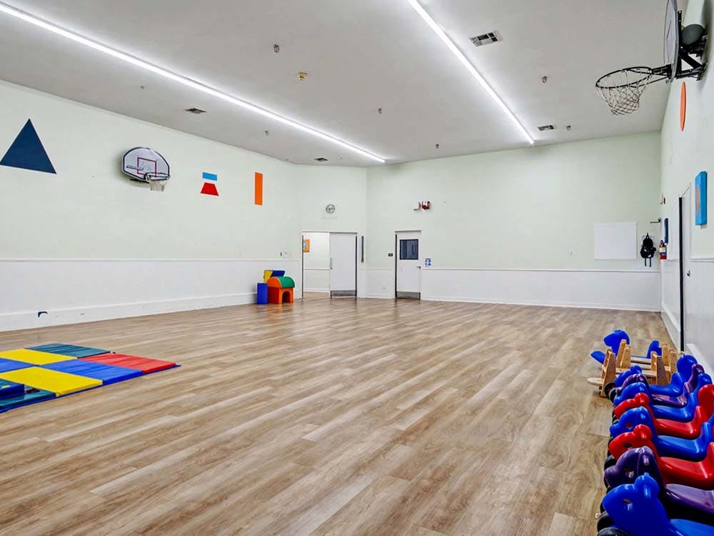 Empty children's playroom with colorful mats and riding toys