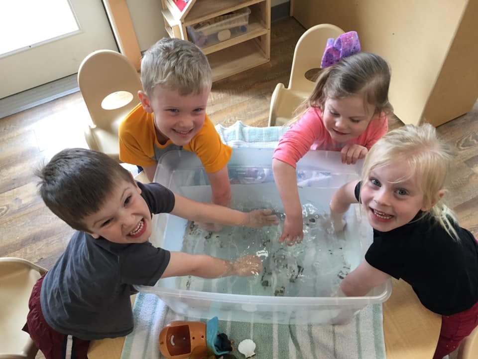Four children playing in a water table