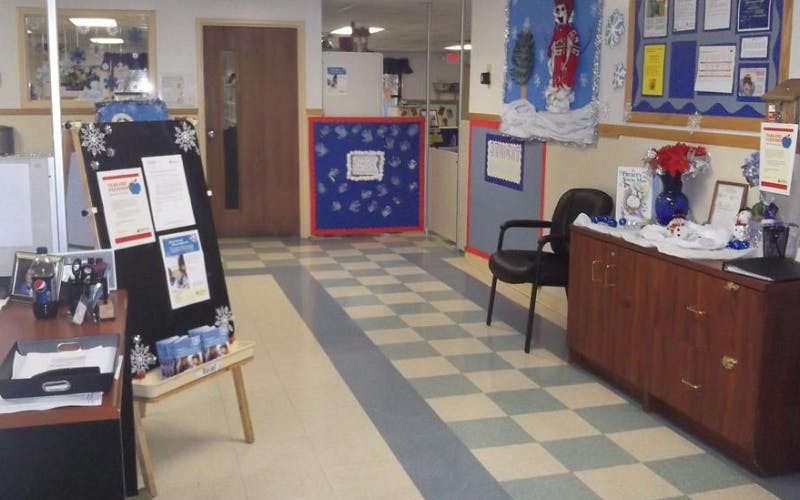 An office hallway with a checkered floor, bulletin boards, and winter decorations