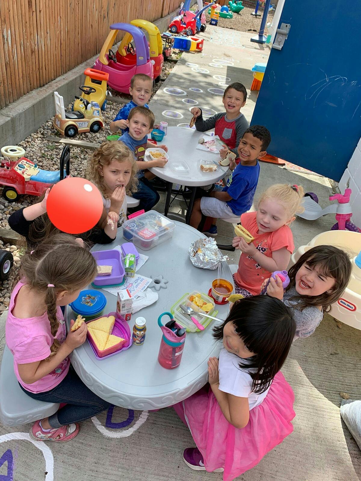 Children eating at small tables outdoors