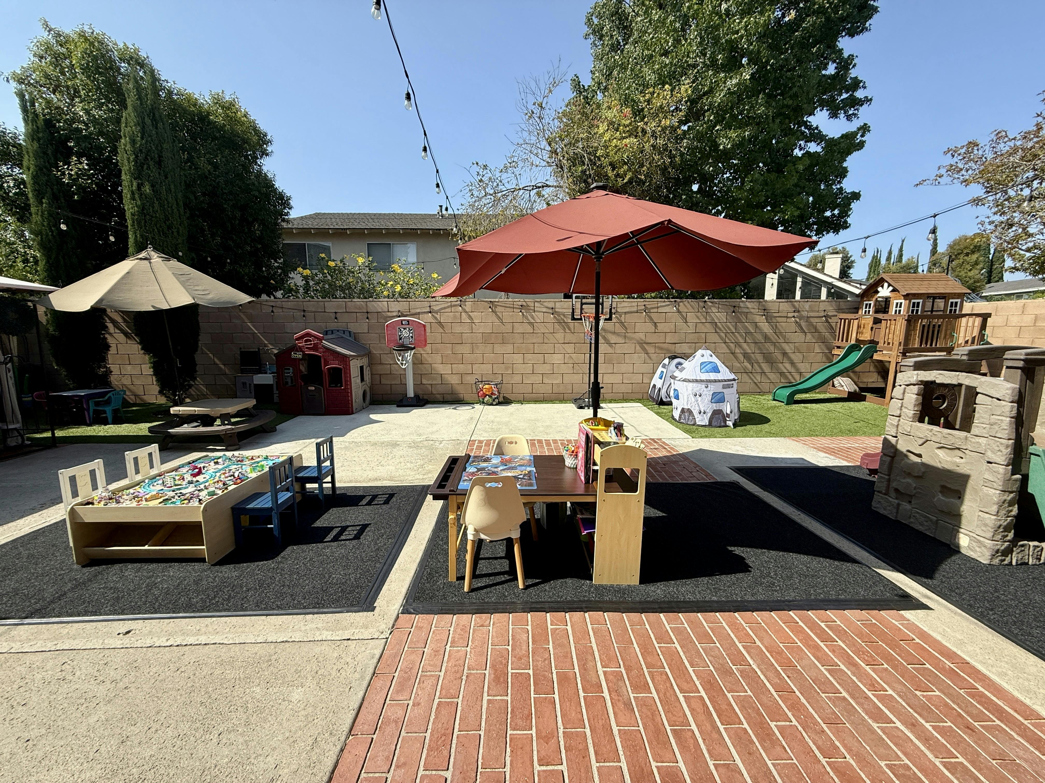 Backyard play area with toy tables, small playhouses, and outdoor furniture