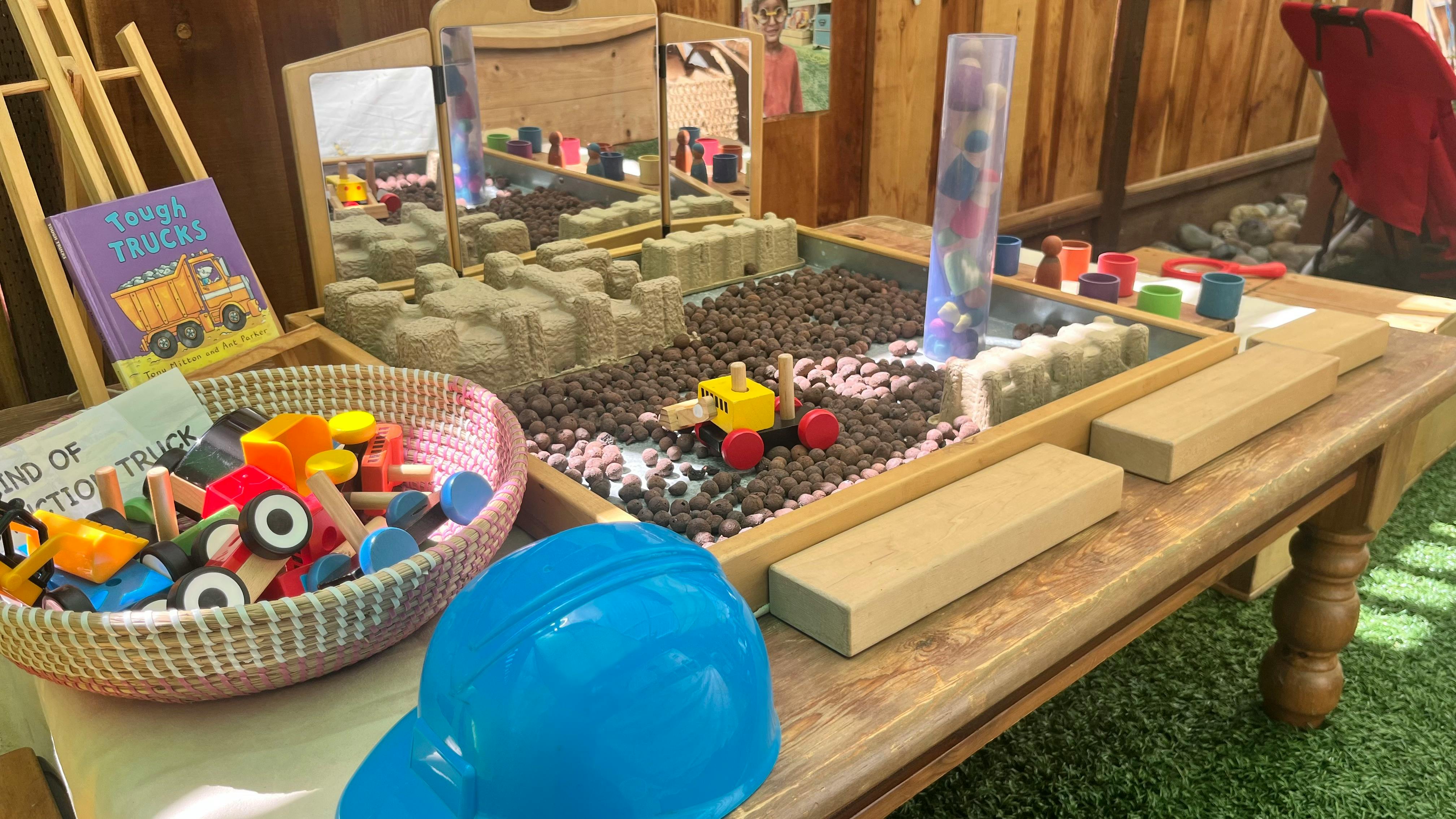 Play area with construction toys, a blue hard hat, and a book