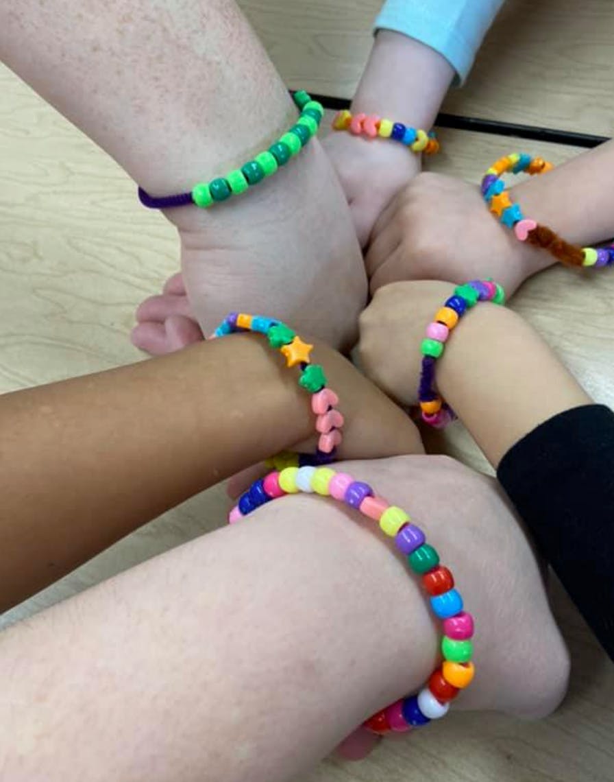 Multiple children's arms with colorful beaded bracelets