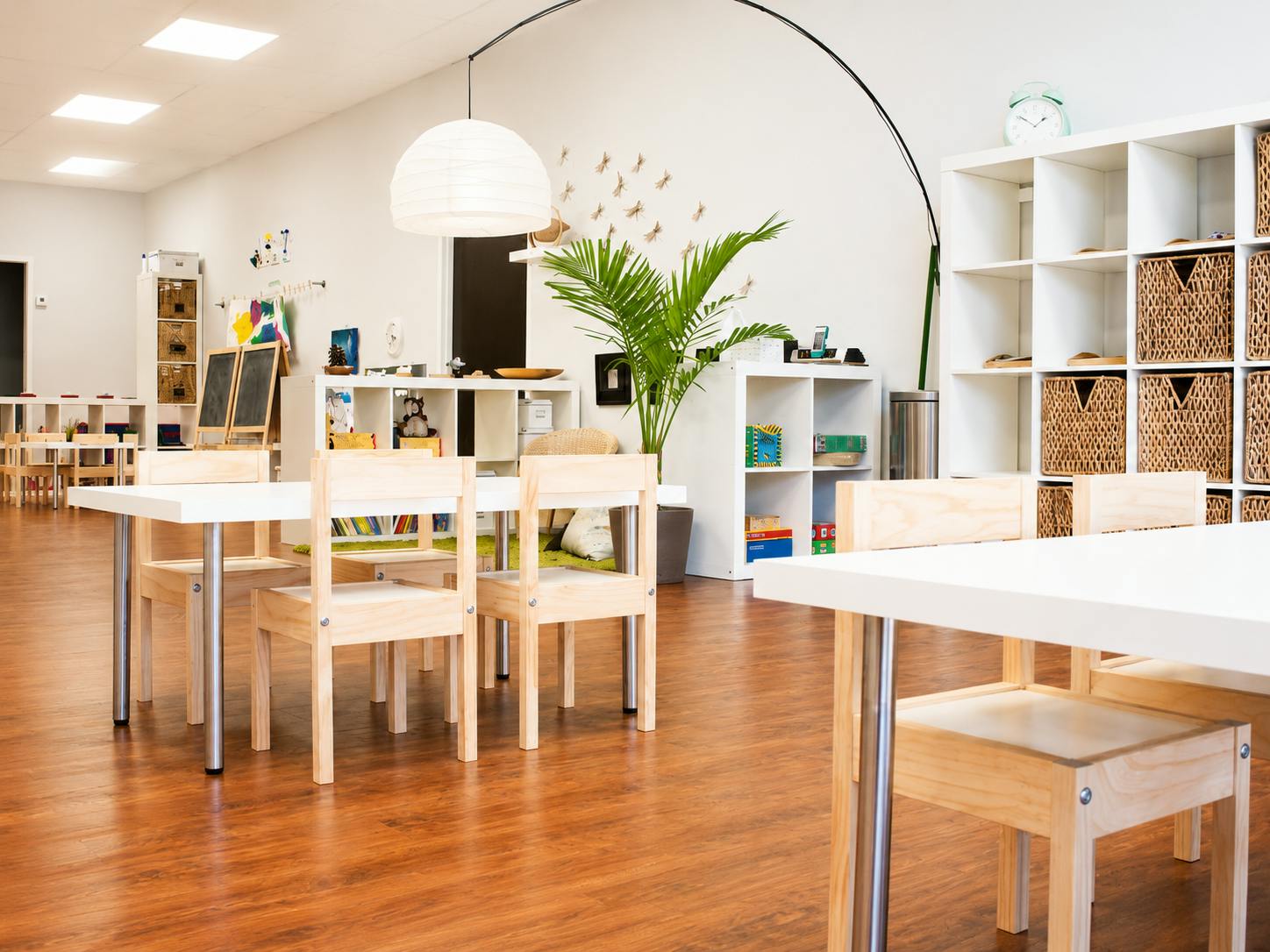Empty children's playroom with small wooden tables and chairs