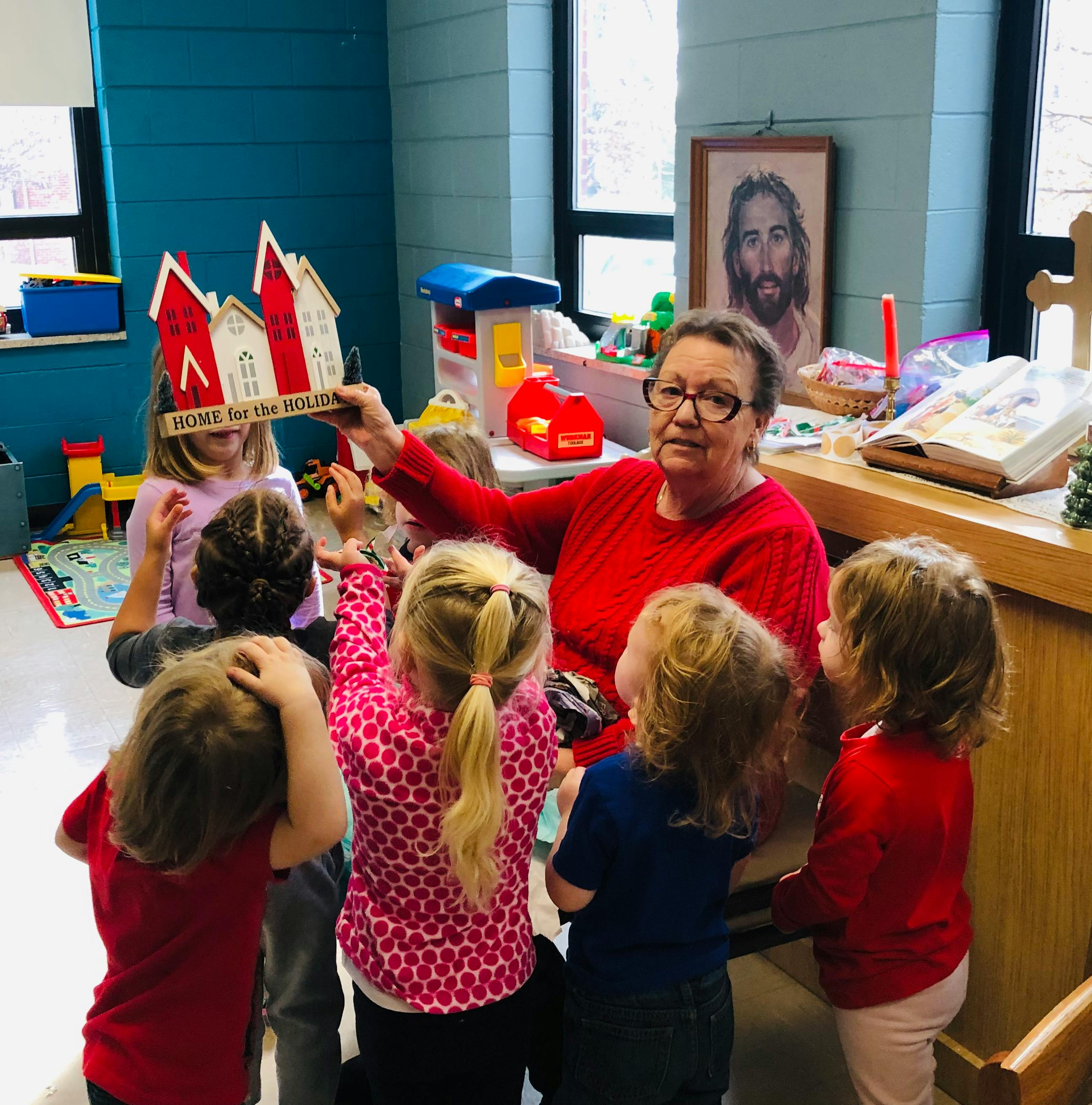 Person showing a house craft to a group of children