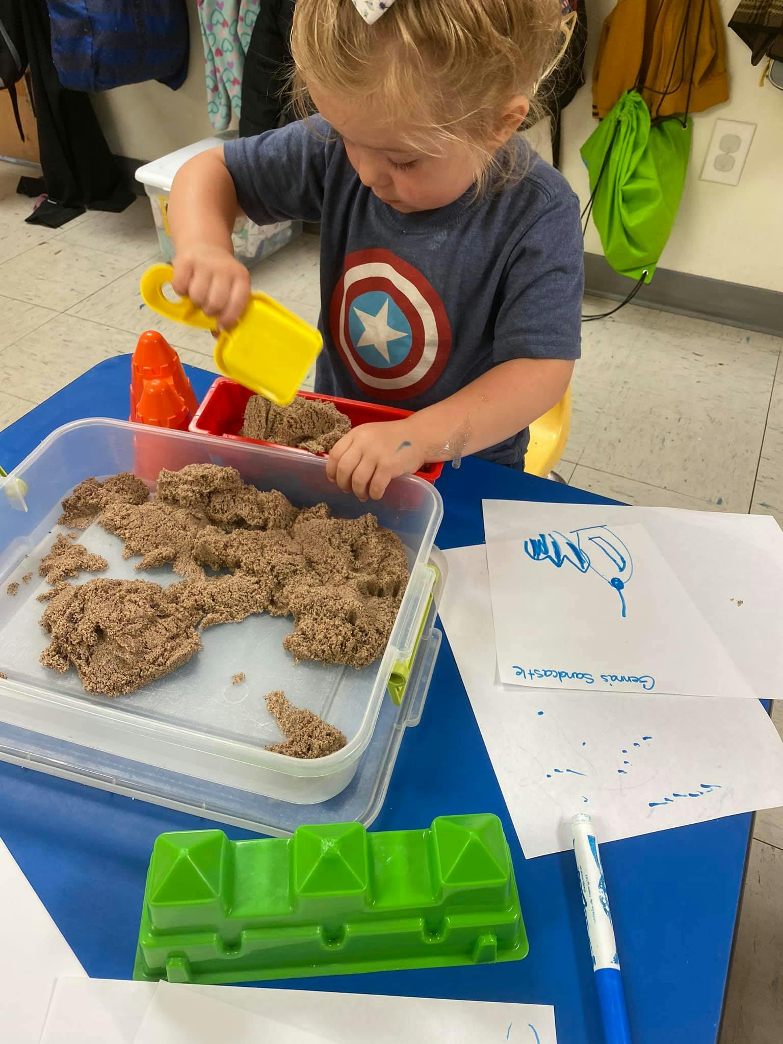 Child playing with kinetic sand at a table