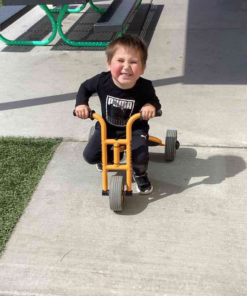 Child riding a tricycle outdoors on a tricycle