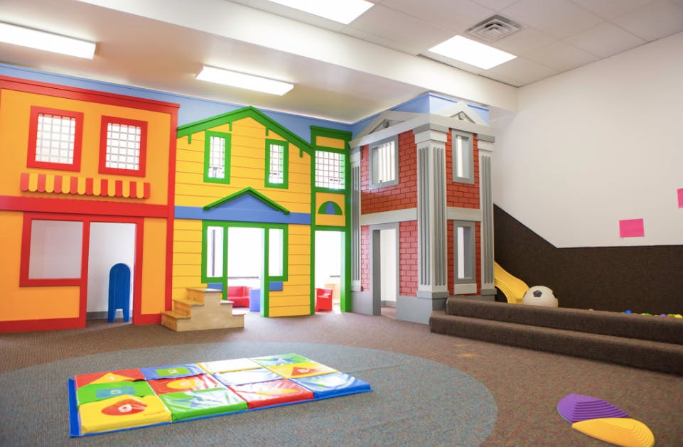 Indoor play area with colorful house facades and a soft play mat