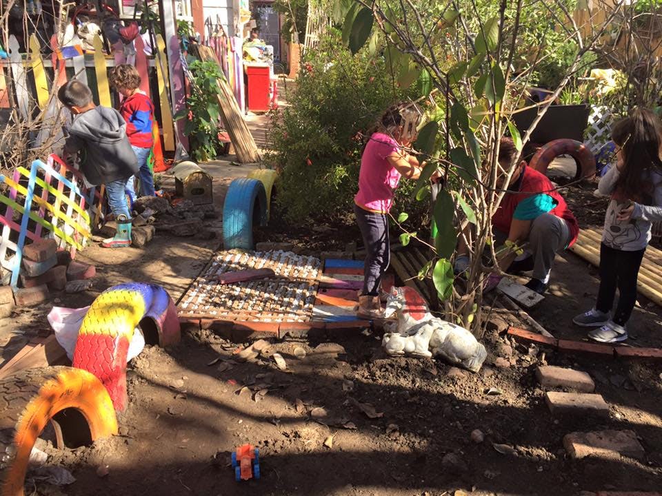 Children playing in a natural outdoor area with plants and colorful objects