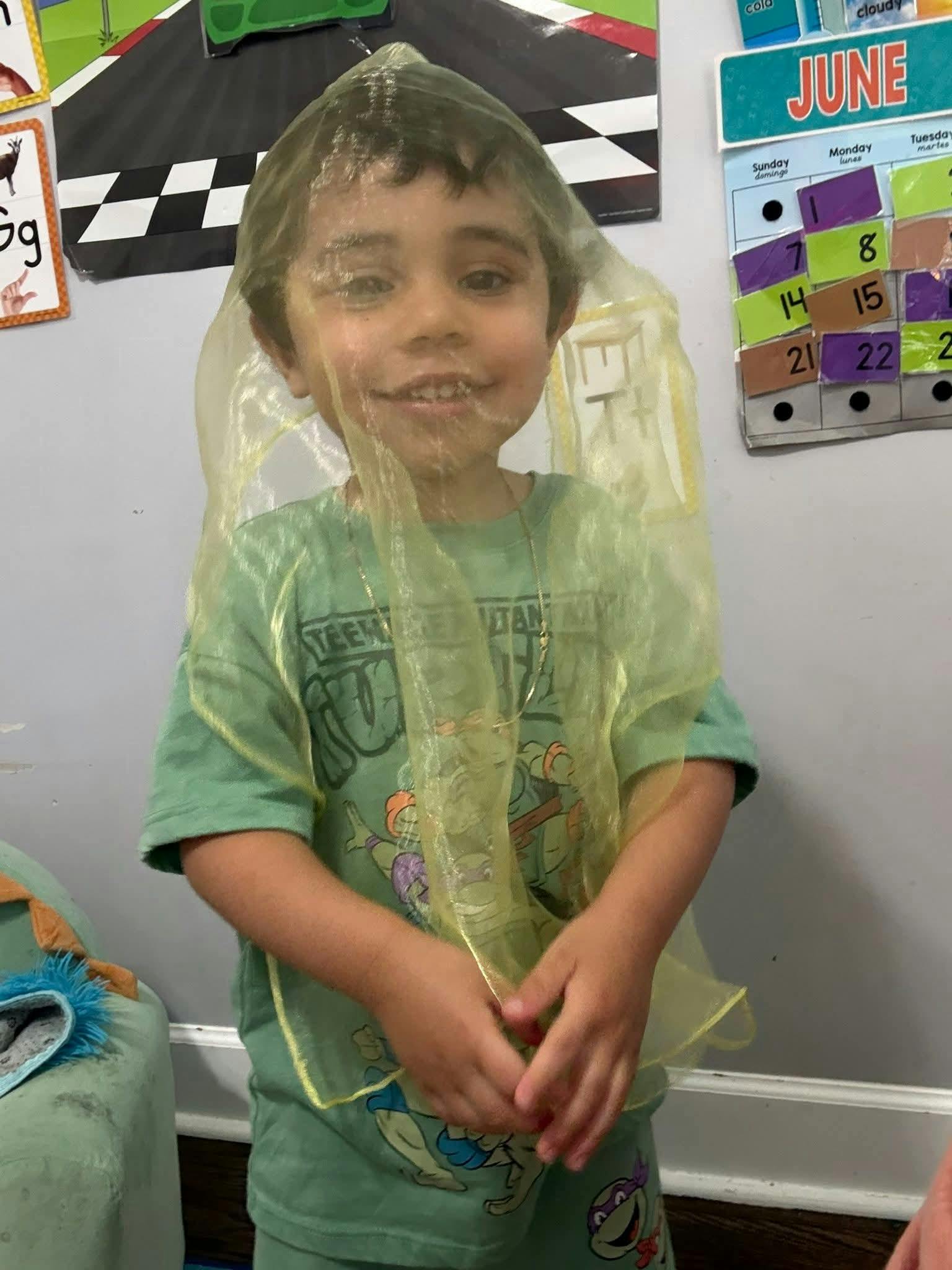 Child wearing a yellow sheer fabric over their head