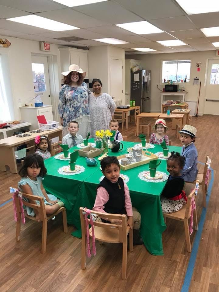 Two adults and several children gathered around a table in a classroom