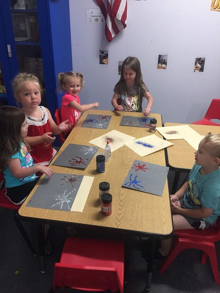 Children sitting at tables doing crafts in-class art projects