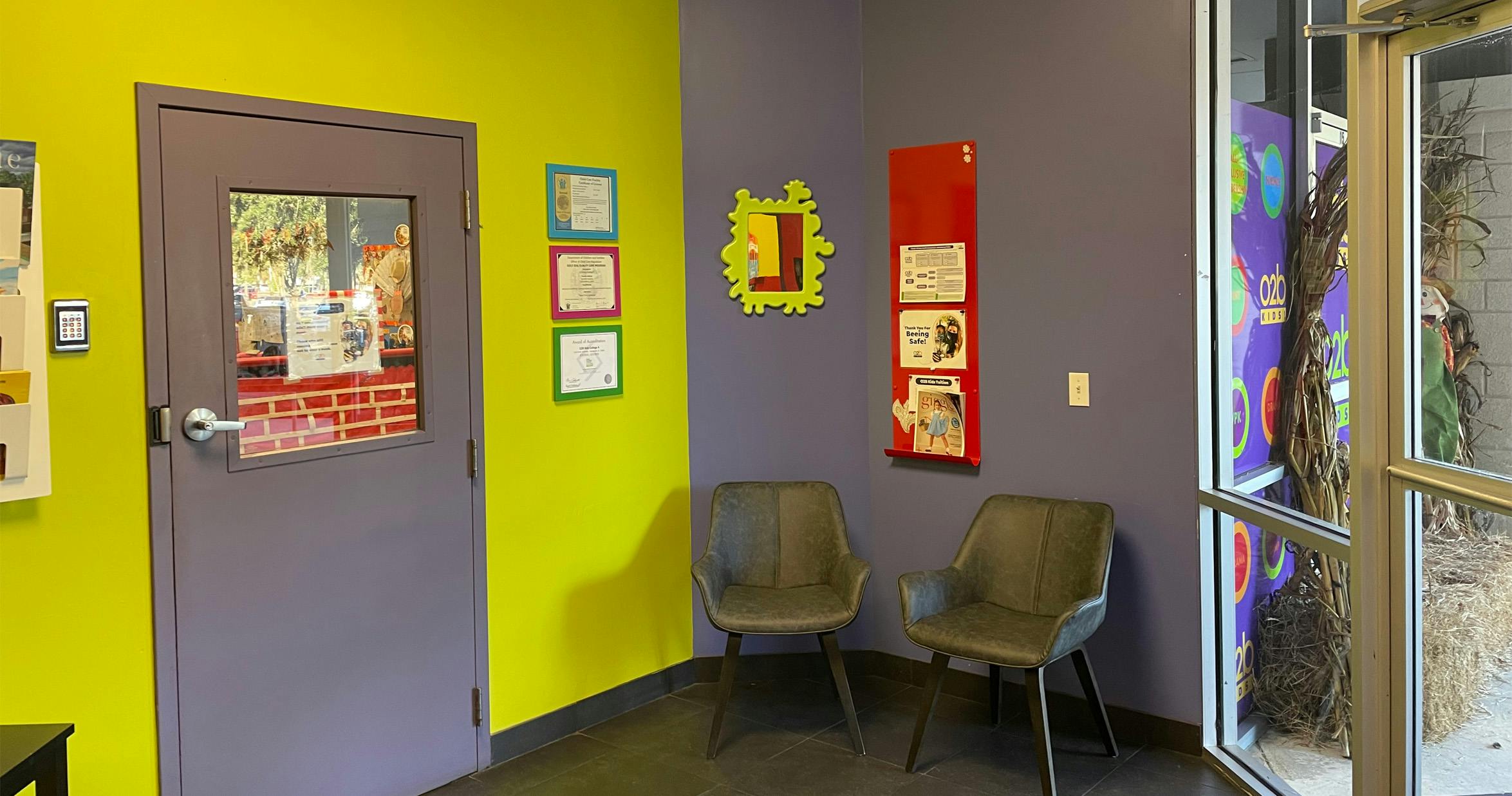 waiting area with bright green and purple walls, two gray chairs