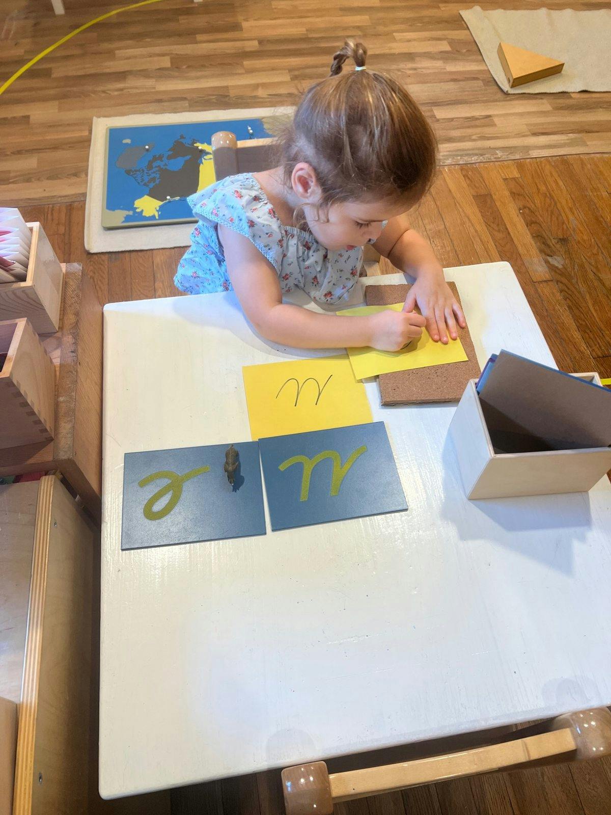 Child practicing handwriting with letter cards at a table