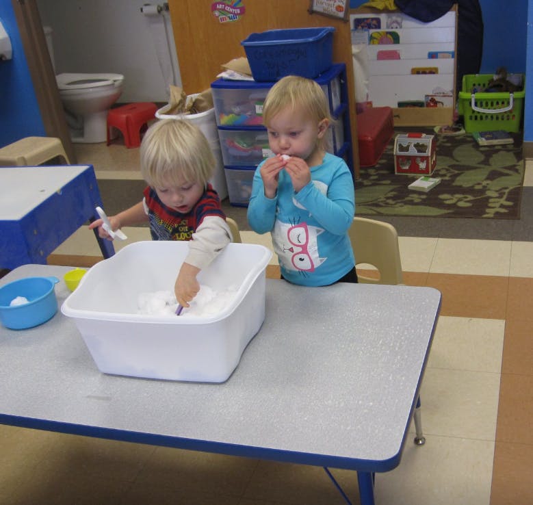 Two children playing with a white tub on a table
