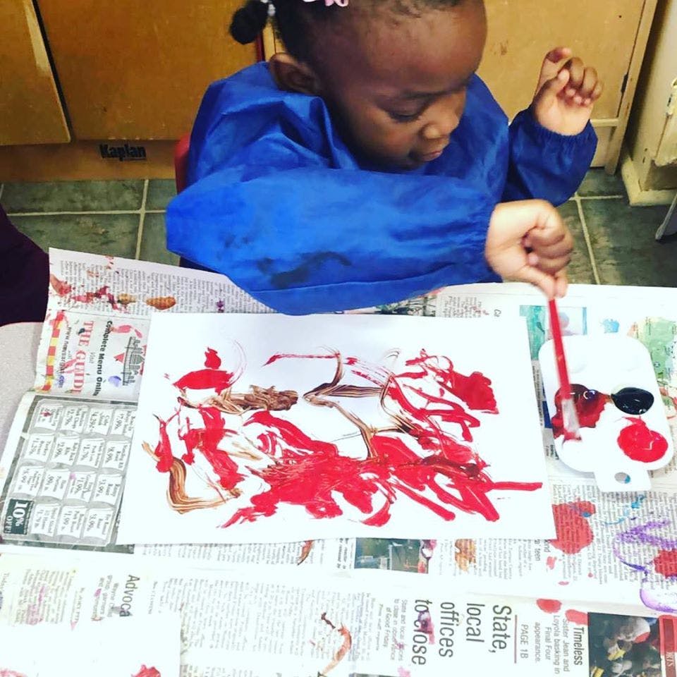 Child painting with red and brown paint on paper