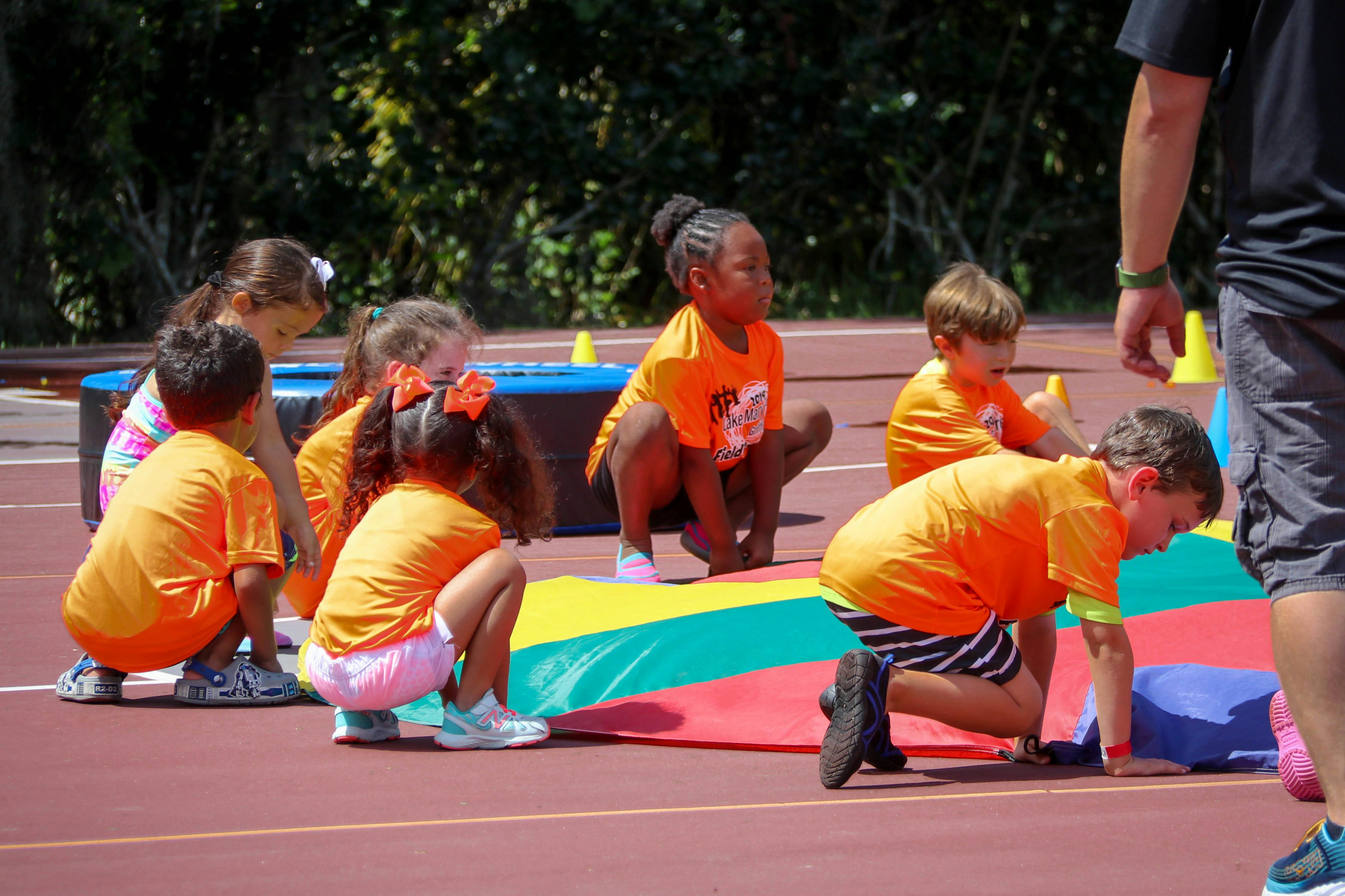 Children in orange shirts crouching on a track