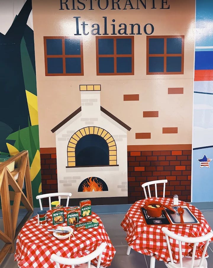Play kitchen with Italian restaurant facade and two tables with red checkered tablecloths