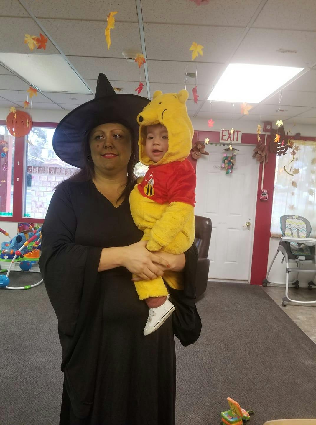 Person in witch costume holding a child in a bear costume