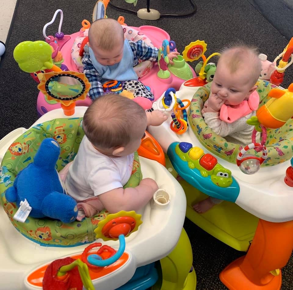 Three babies in infant activity centers