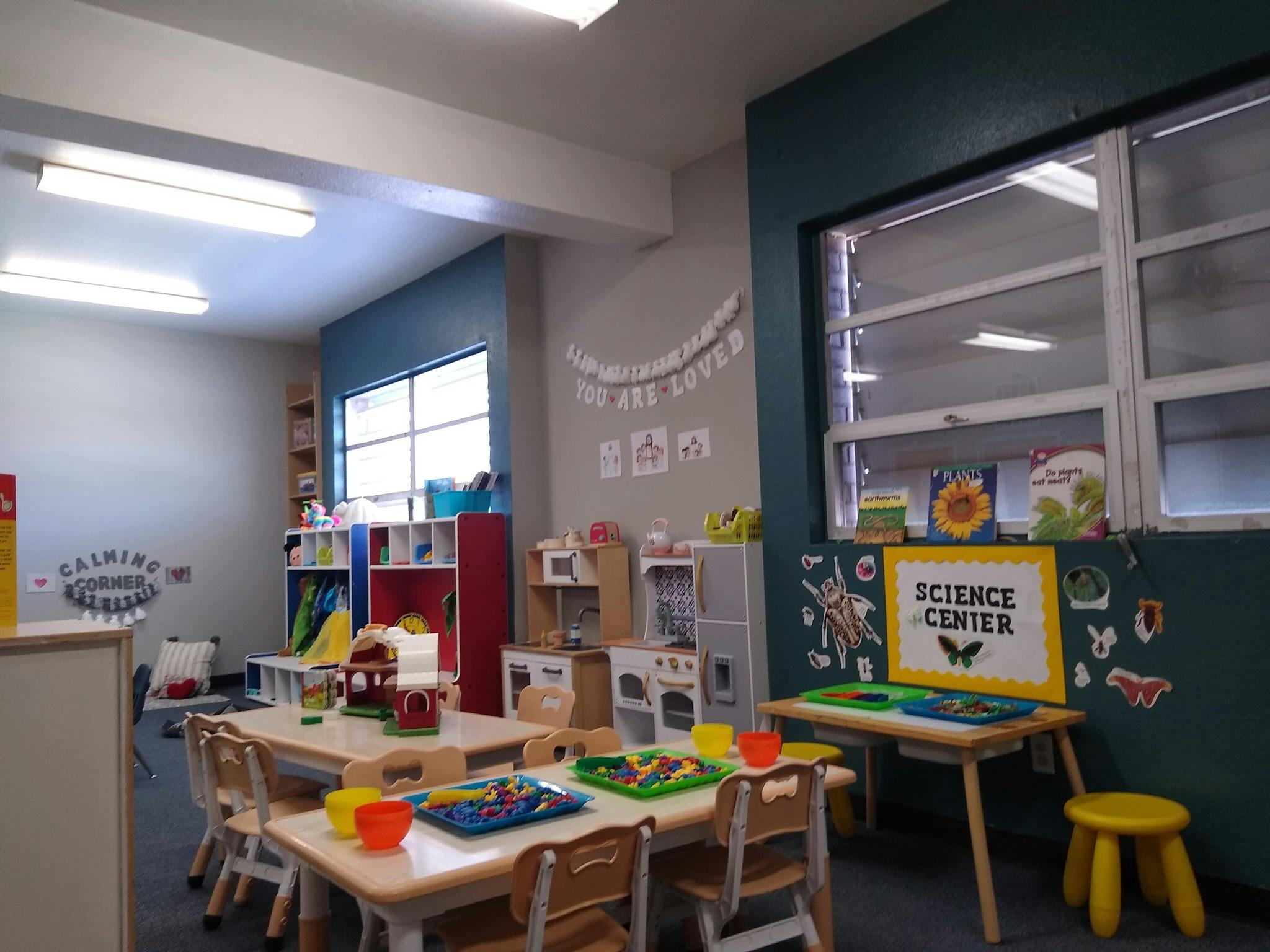 Classroom with small tables, chairs, play kitchen, and a science center