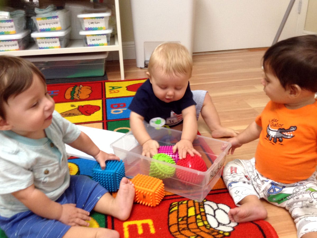 Three children playing with sensory toys in a classroom