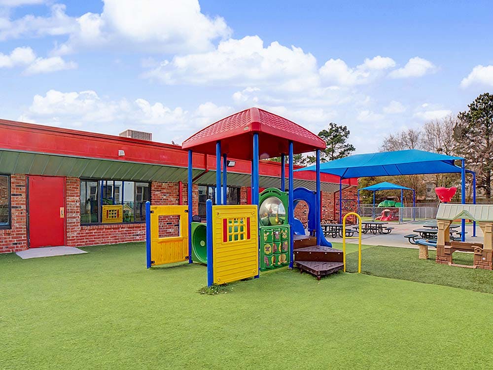 Playground with colorful play structures and a brick building