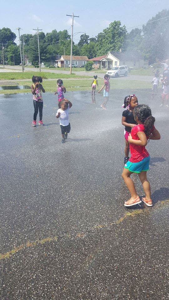 Children playing in water on an asphalt surface